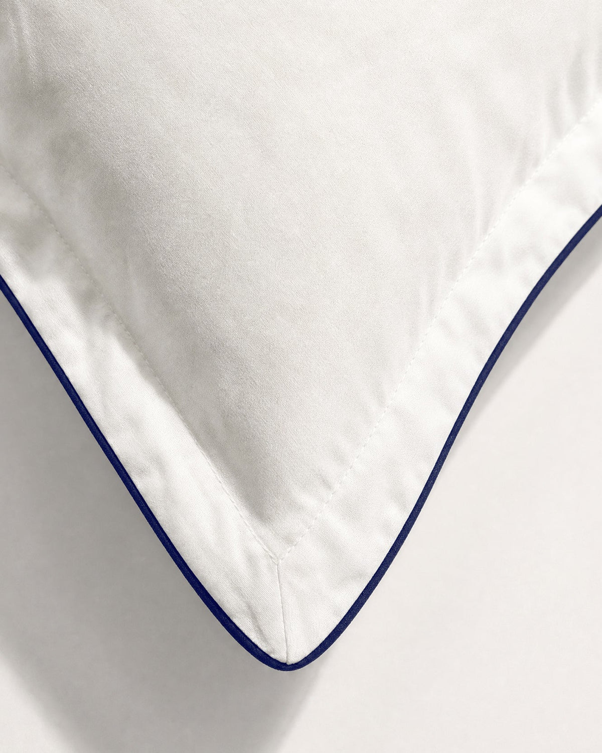 Close-up of Porto pillowcase white fabric, stitched border, and midnight blue piping