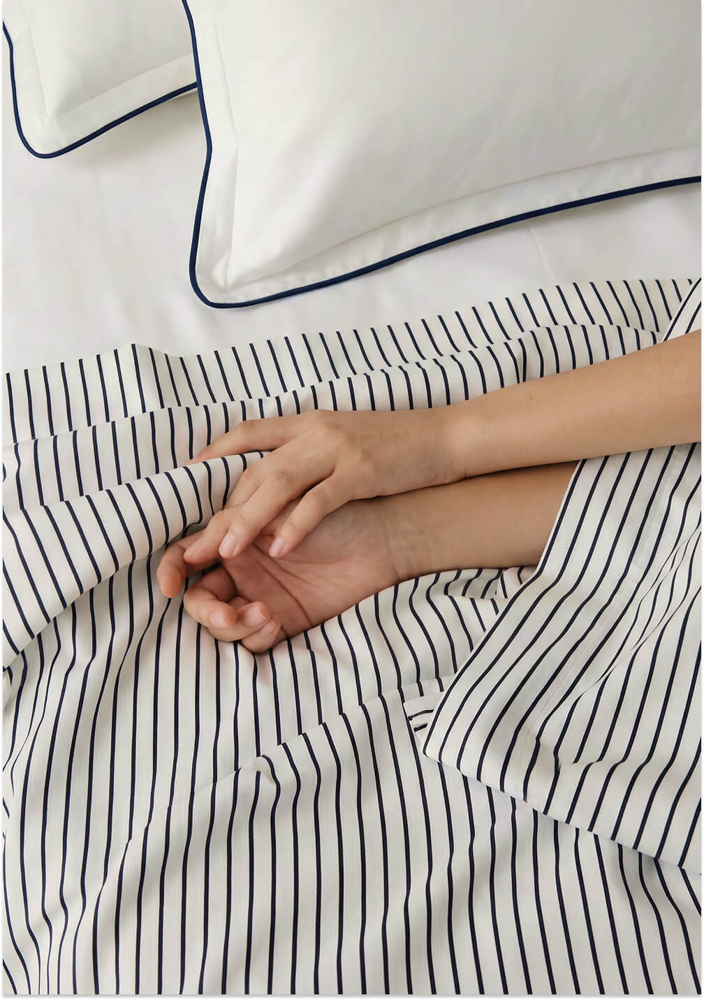 Person resting their hands on the Porto white and midnight blue striped top sheet