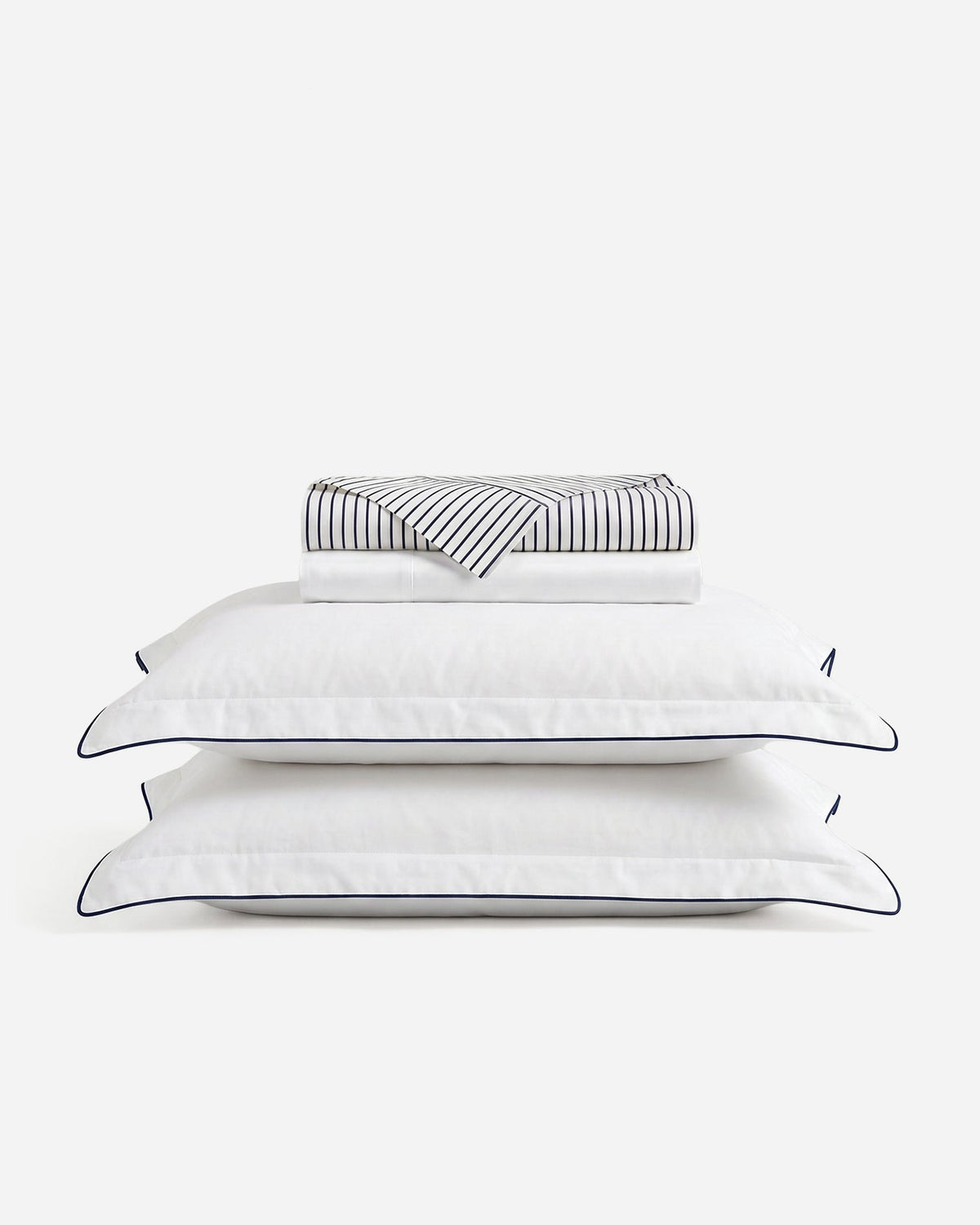Porto sheet set with folded striped and white sheets above two blue-trimmed white pillowcases