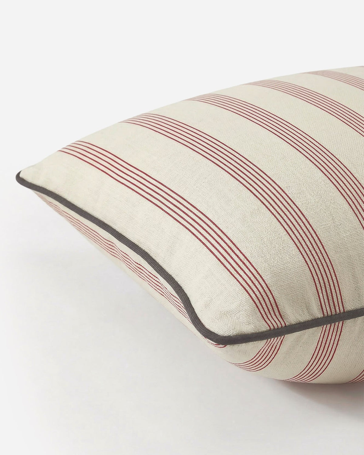 Close-up of the Rimini pillow showing textured cotton fabric, terracotta stripes, and charcoal piping
