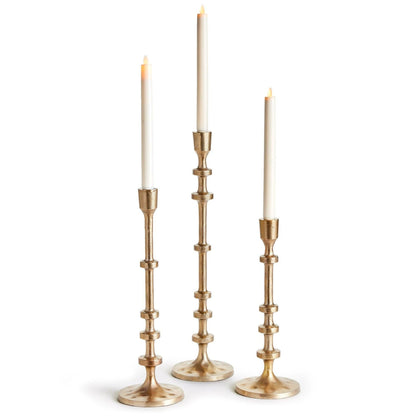 three gold taper candle holders with candles