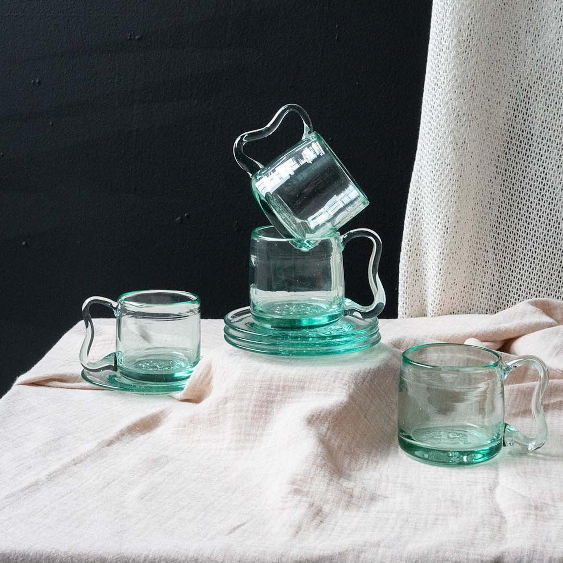 a table topped with two glass cups and a pitcher