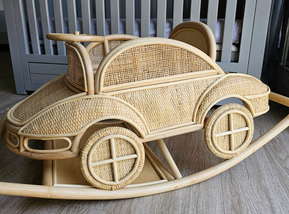 Side detail of the rattan rocking car showing its woven body, decorative wheels, and curved base