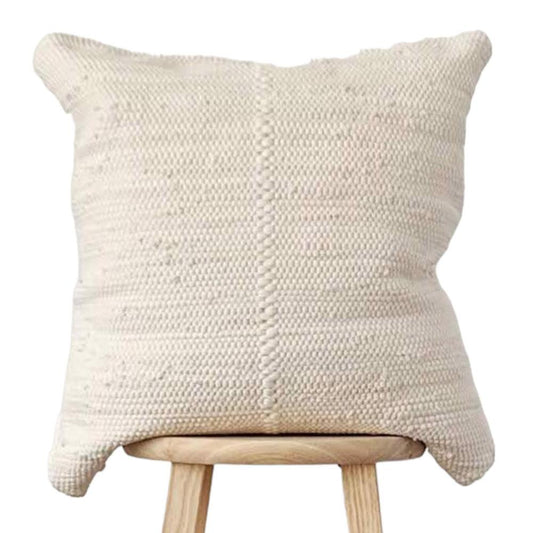 a white pillow sitting on top of a wooden stool